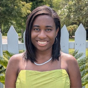 A Black woman with shoulder length straight hair and a green corset stands outside